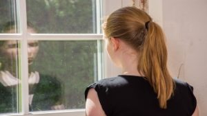 Caregiver looking at reflection in window