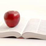 An apple on an open text book.